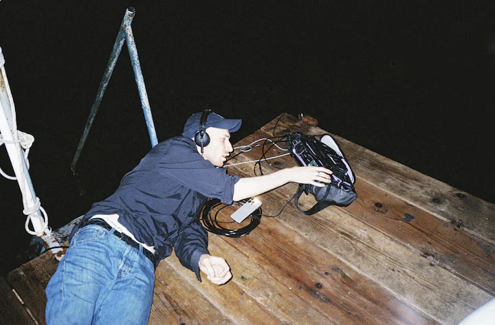 Daniel Blumberg setting up his recording equipment on a pier